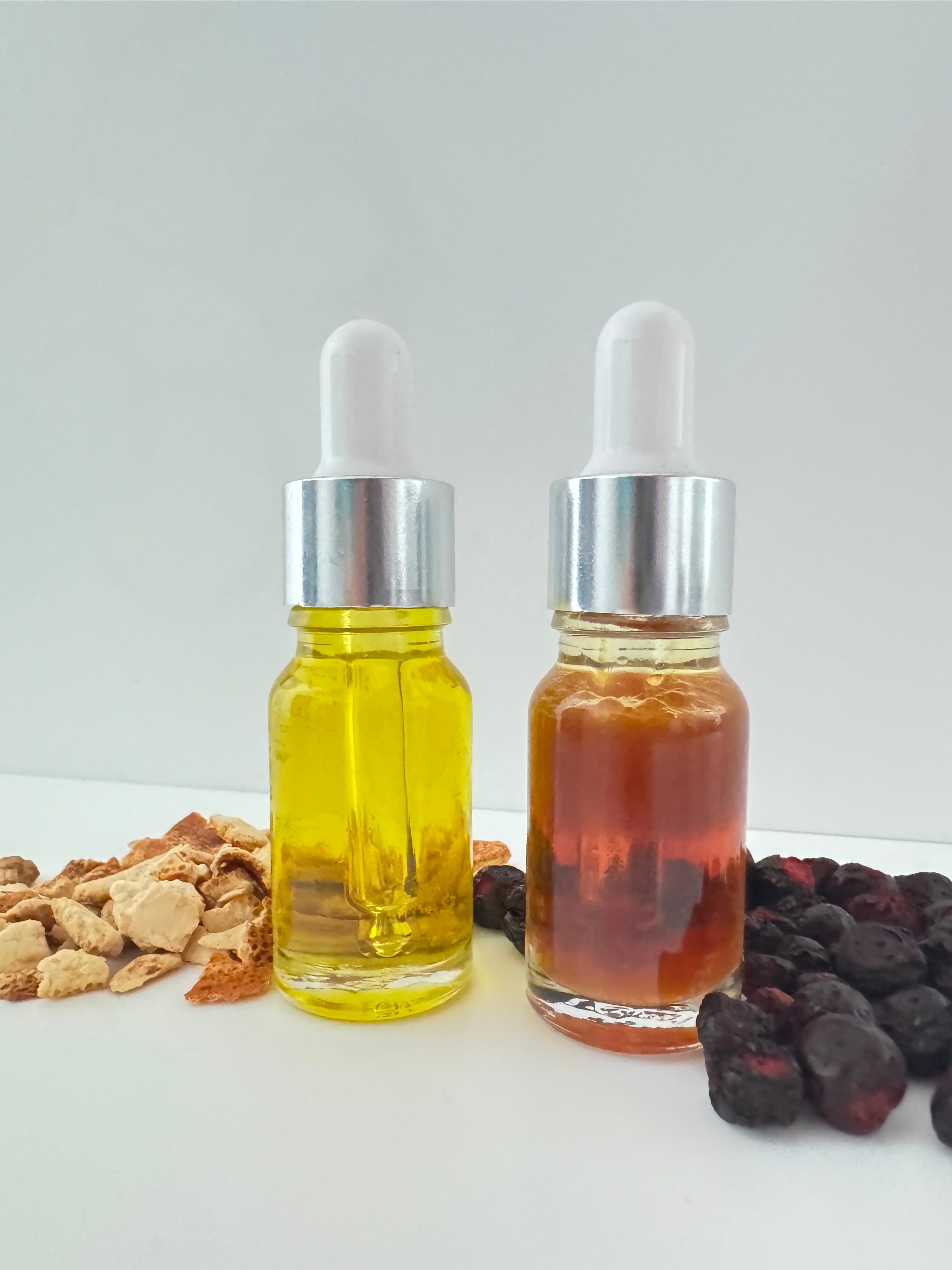 Frascos conta-gotas com óleos amarelo e âmbar, ladeados por cascas de laranja e bagas secas.