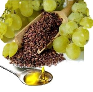 Uvas verdes, sementes em colher de madeira e óleo dourado vertido em uma colher.